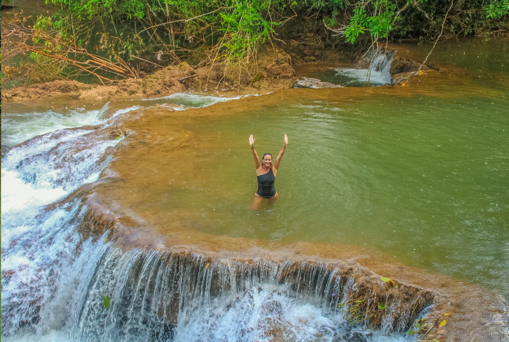 Mulher faz pose para foto em piscina natural na Estância Mimosa passeio de cachoeiras em Bonito MS.