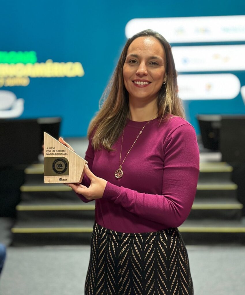 Camila Fernandes, coordenadora, do Programa Del Turismo no Senac MS segura o prêmio da Estância Mimosa.